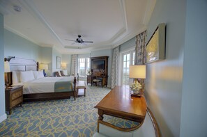 A hotel room with a bed, desk, chair, and a ceiling fan.