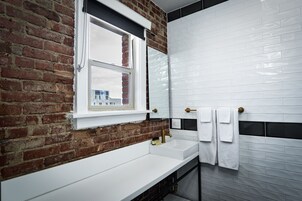 A bathroom with a white sink, a window, and a mirror.