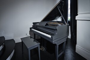Un pianoforte a coda in una stanza con pavimento nero e pareti bianche.