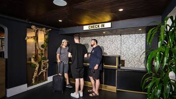 Ein Empfangsbereich mit einem 'CHECK IN'-Schild, einer Holzwanddekoration und einer Rezeption.