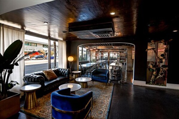 A modern lounge area with a leather sofa, blue armchairs, and a coffee table. - H Hotel (Los Angeles)