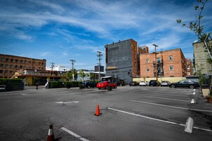 Un estacionamiento con coches, un coche deportivo rojo, y un edificio con un letrero que dice 'LAVANT'.