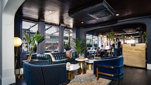 A modern lounge area with leather sofas, a patterned rug, and a reception desk. - H Hotel (Los Angeles)