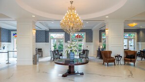 A lobby with a round table, chairs, a chandelier, and a vase with flowers. - The Inn at Ole Miss (University)