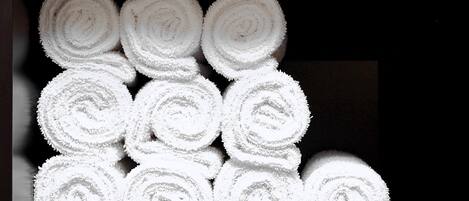 Neatly stacked white towels in a dark room.