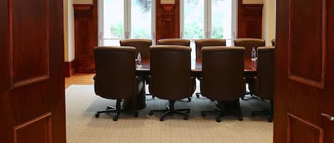 Ein McMillan Konferenzraum mit Holzboden, großen Fenstern und einer Chandelierleuchtre.