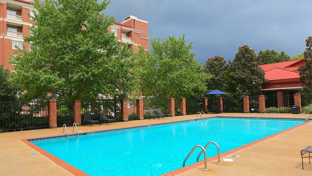 A rectangular swimming pool with clear blue water, surrounded by a brick deck and metal railings. - The Inn at Ole Miss (University)