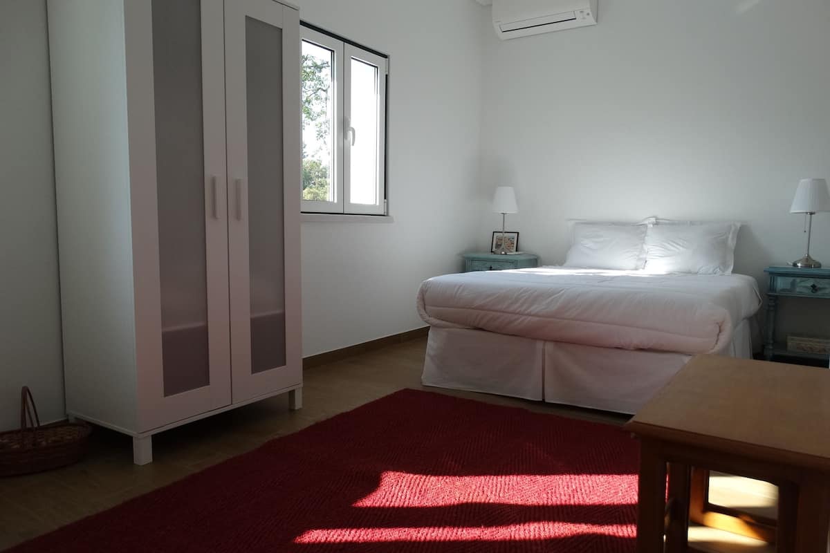 A bedroom with a bed, a nightstand, a wardrobe, and a window.