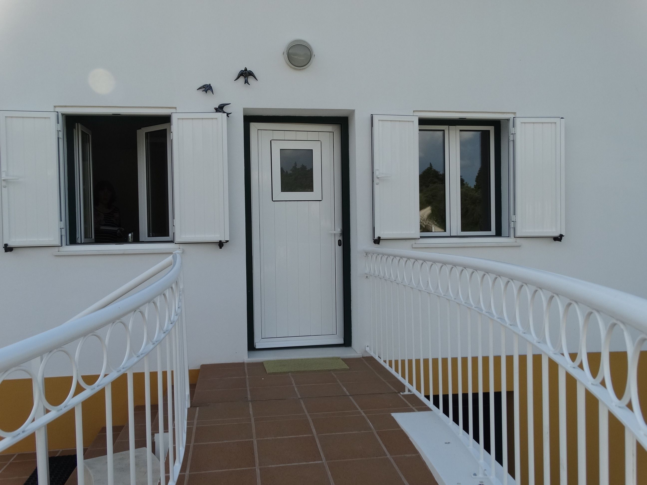 A building with white exterior walls, a central door, and two windows with white shutters.