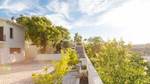 A courtyard with a paved walkway, a white building, and lush greenery. - Aires da Serra Hotel (Torres Novas)