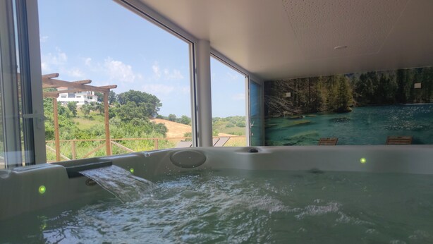 A hot tub with a view of a forested landscape and a building in the background. - Aires da Serra Hotel (Torres Novas)