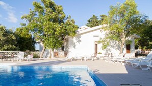 A pool area with a white building, lounge chairs, and trees. - Aires da Serra Hotel (Torres Novas)