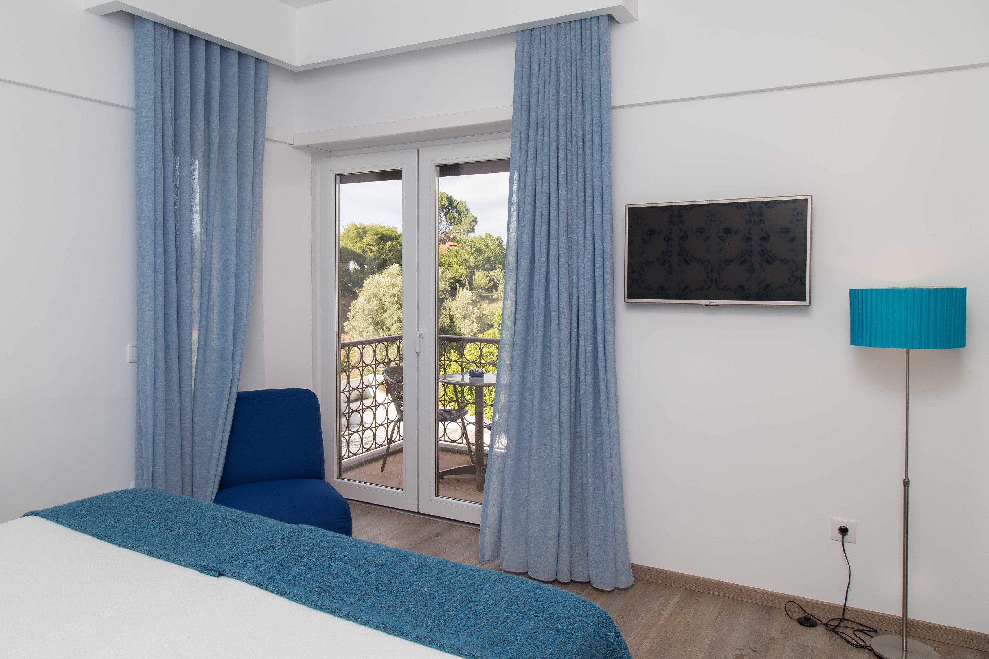 Een hotelkamer met een bed, een stoel, een televisie en uitzicht op het omliggende landschap.