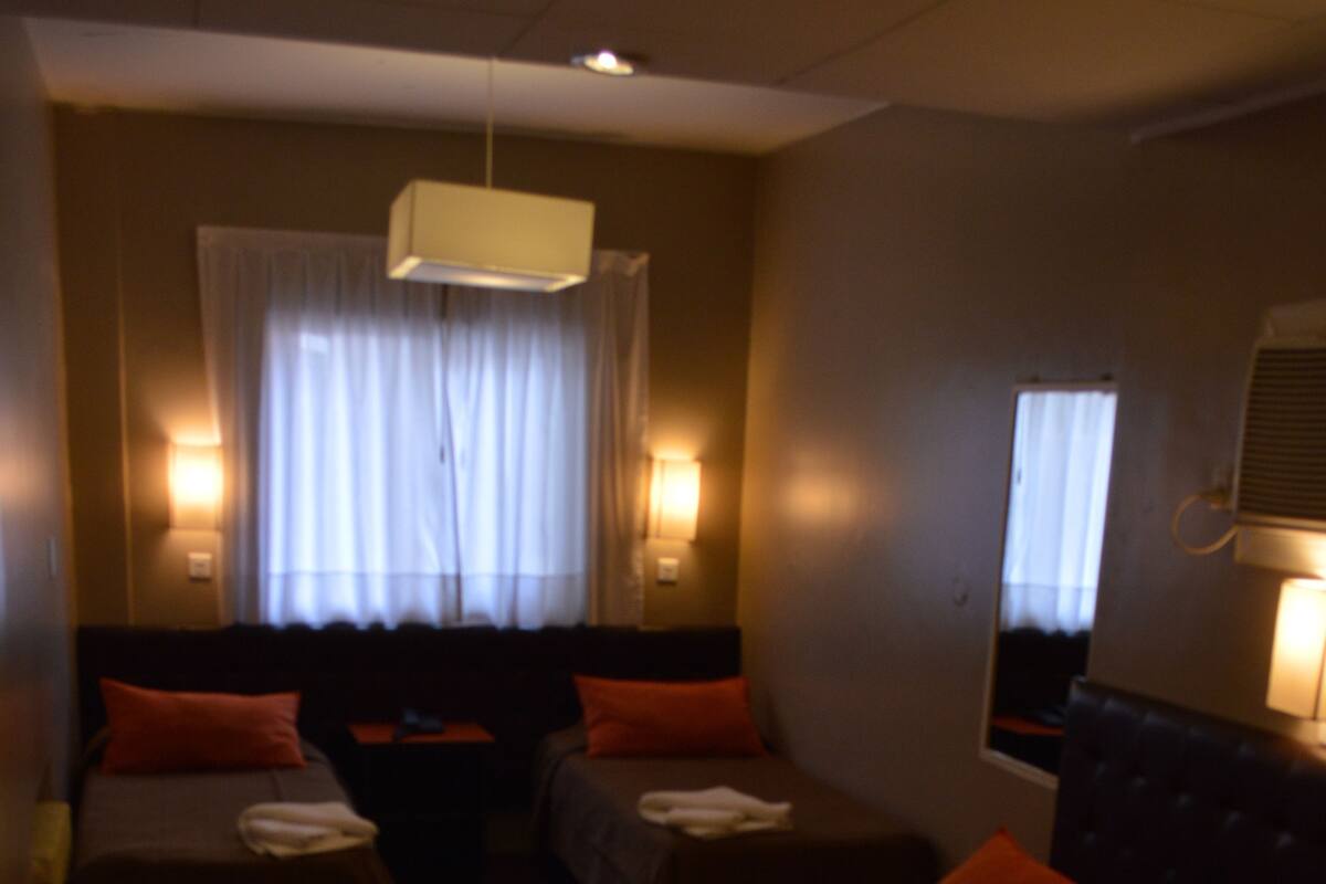 A hotel room with two single beds, a sofa, and a small table.