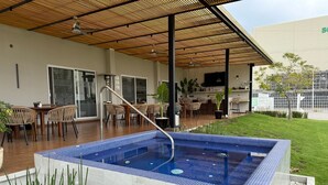 Un espace piscine extérieur moderne, doté d’une terrasse carrelée, d’un coin salon abrité et offrant une vue sur le paysage environnant.