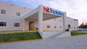Un hôtel moderne, avec une façade plate, un hall d’entrée abrité et un escalier menant à l’entrée.