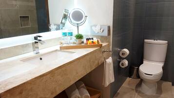 Un baño moderno con un espejo grande, un lavamanos, un inodoro y una pequeña planta en maceta.