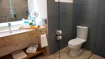 Un baño moderno con tocador de mármol, cabina de ducha de vidrio y un inodoro.
