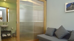 Une salle de bain avec un plancher en bois, un lavabo, des toilettes et une douche dotée d’une porte en verre.