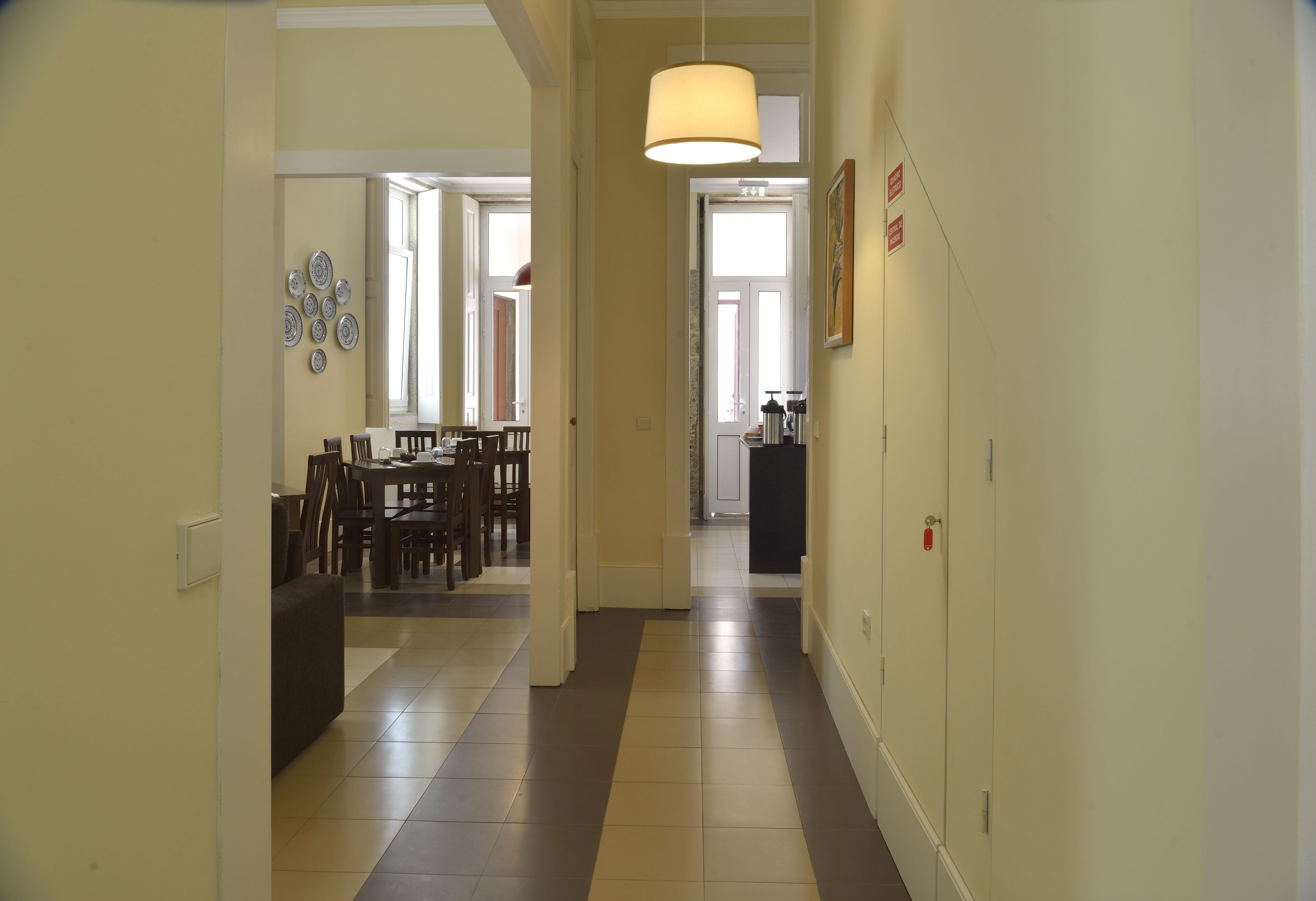 A hallway with a dining area, a coat rack, and a door leading to another room.