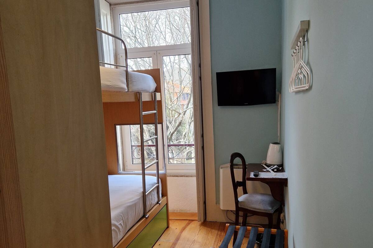 Ein Zimmer mit Etagenbetten, einem Schreibtisch, einem Stuhl und einem Fernseher.