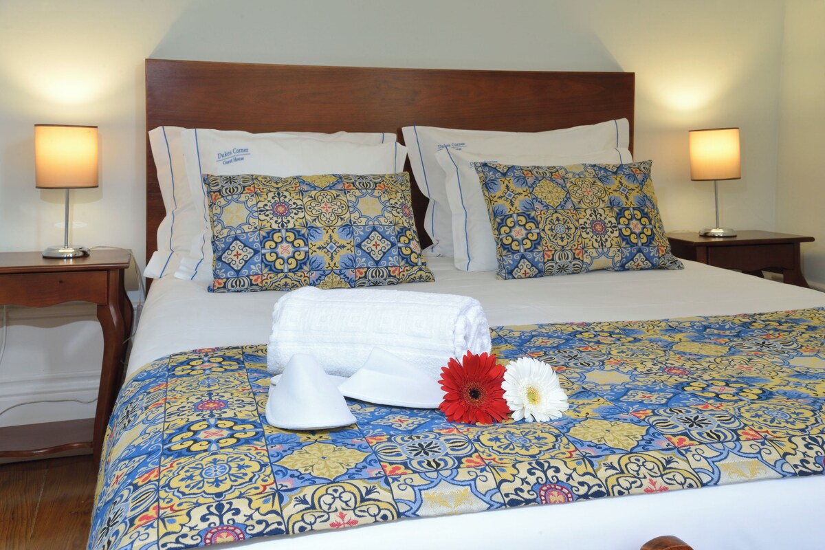 A neatly made bed with patterned bedding, two bedside lamps, and a wooden headboard.