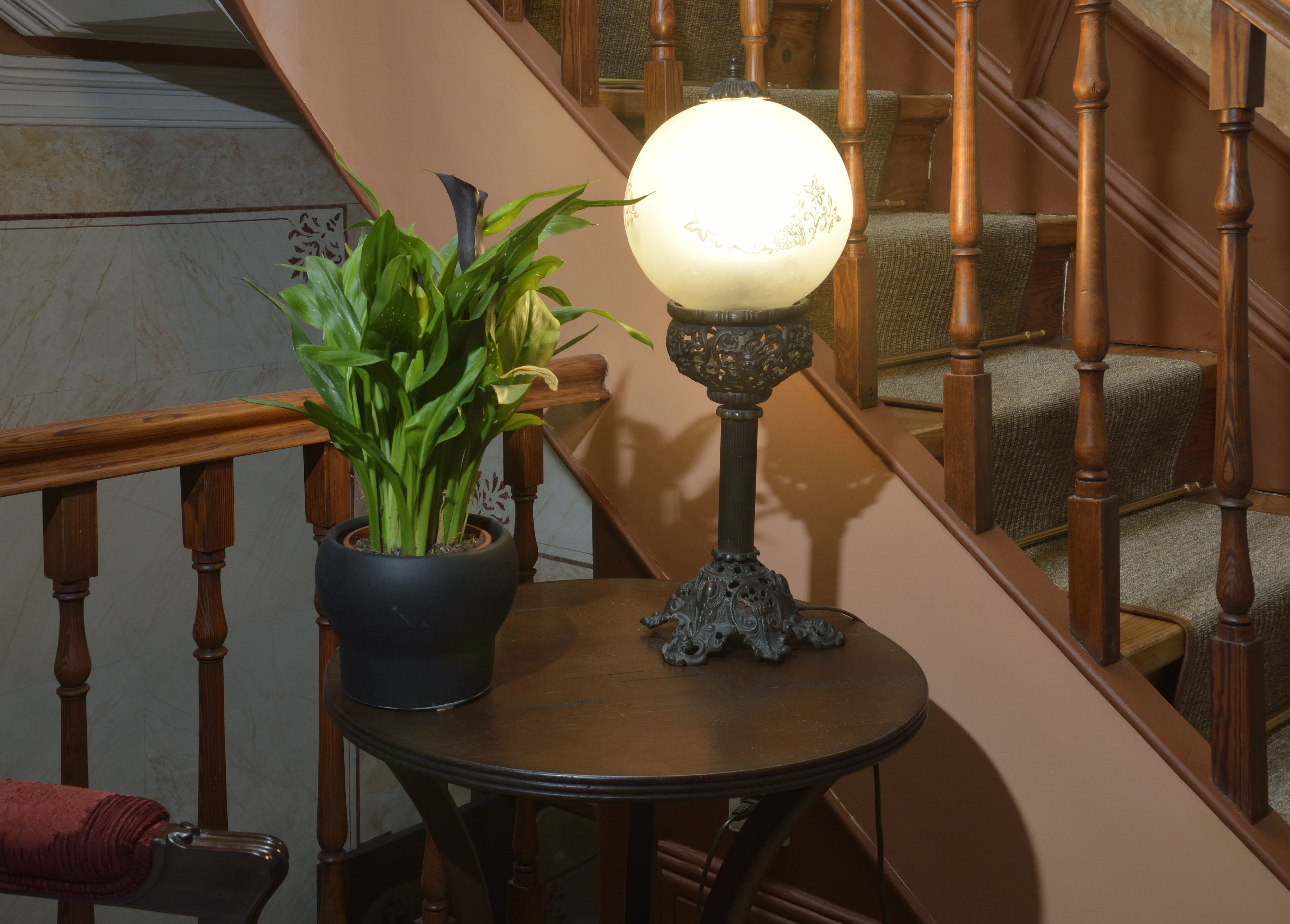 A staircase with wooden railings and a potted plant on a small table beside it.