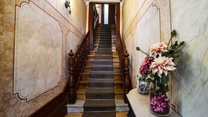 Un magnifique escalier, avec un mur de marbre d’un côté et un vase de fleurs de l’autre.