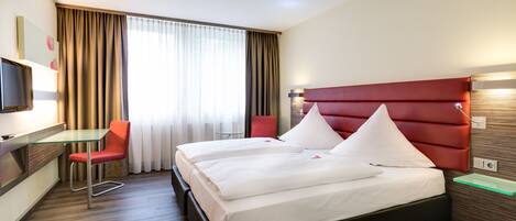 Una habitación de hotel con una cama, un escritorio, una silla y un televisor.
