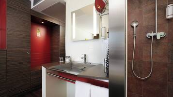 Uma casa de banho moderna com chuveiro, pia e espelho.