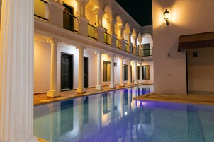 Una piscina que refleja columnas y un balcón.
