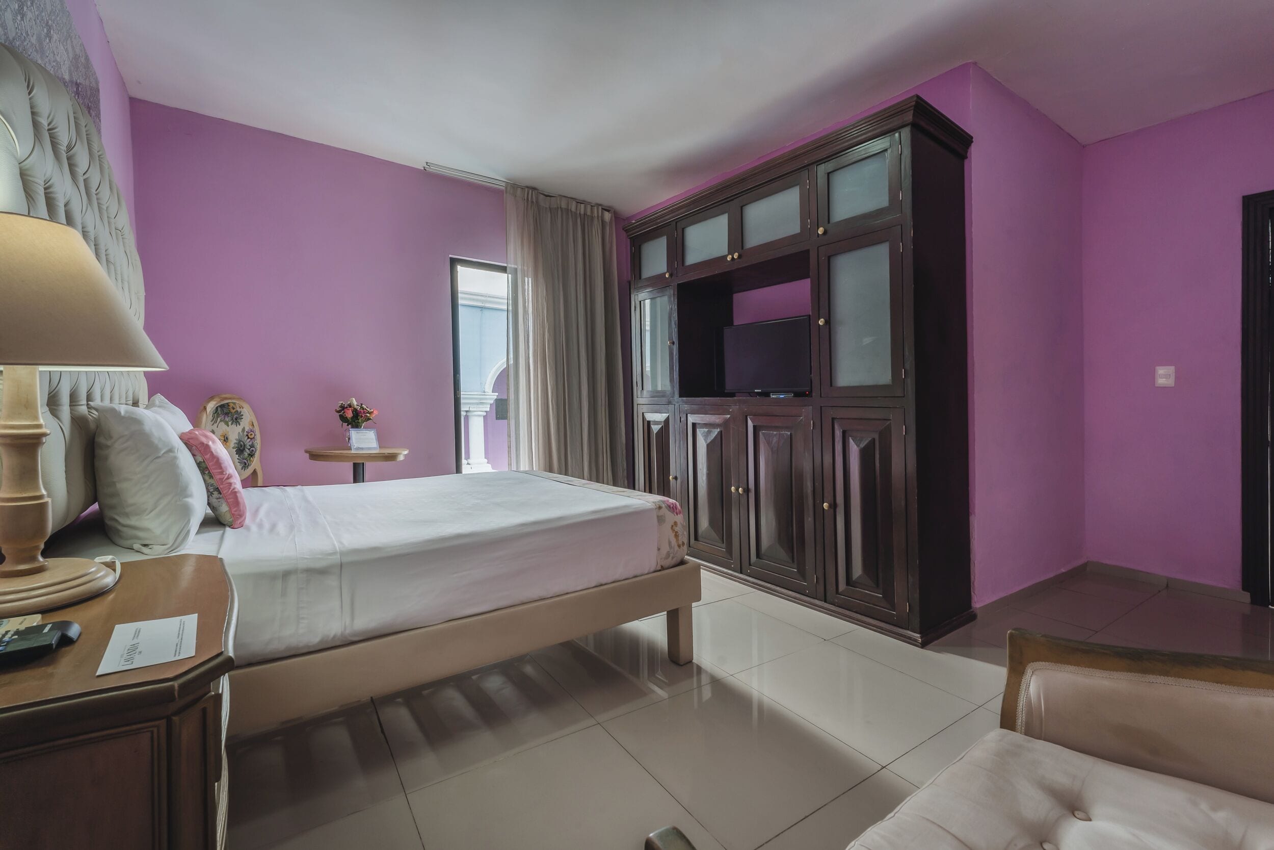 A bedroom with a bed, a TV cabinet, a bedside table, and a chair.