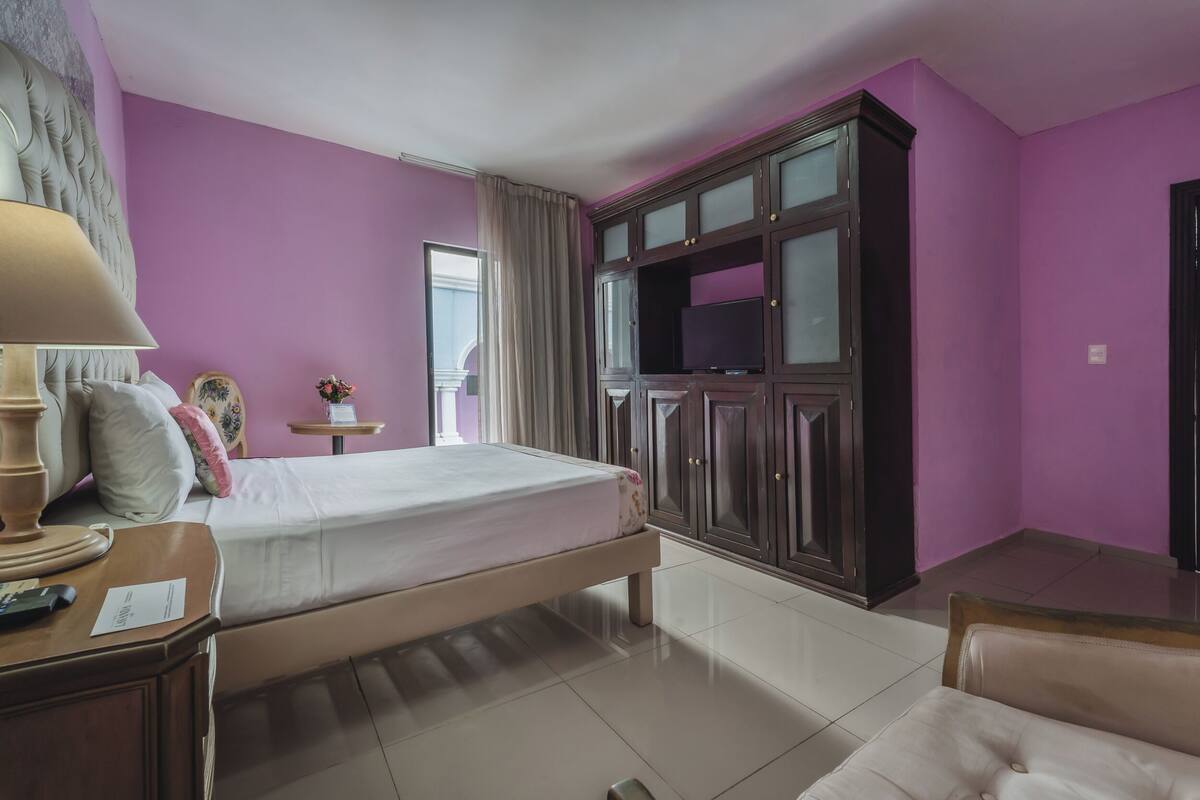 Quarto com cama, móvel para TV, mesa de cabeceira e uma cadeira.