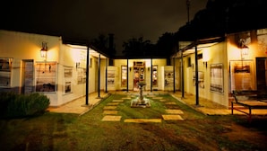 A courtyard with a fountain, surrounded by buildings with illuminated windows and doors. - Hostel Punta Ballena Bar (Punta Ballena)