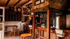 A rustic kitchen with wooden furniture, a bar area, and a dining table. - Hostel Punta Ballena Bar (Punta Ballena)