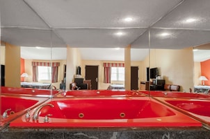 A hotel bathroom with multiple red sinks and mirrors.