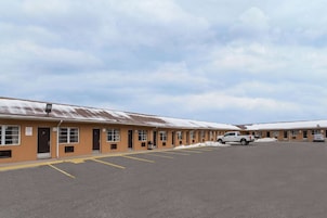 A motel with multiple rooms, a parking lot, and a snow-covered roof.