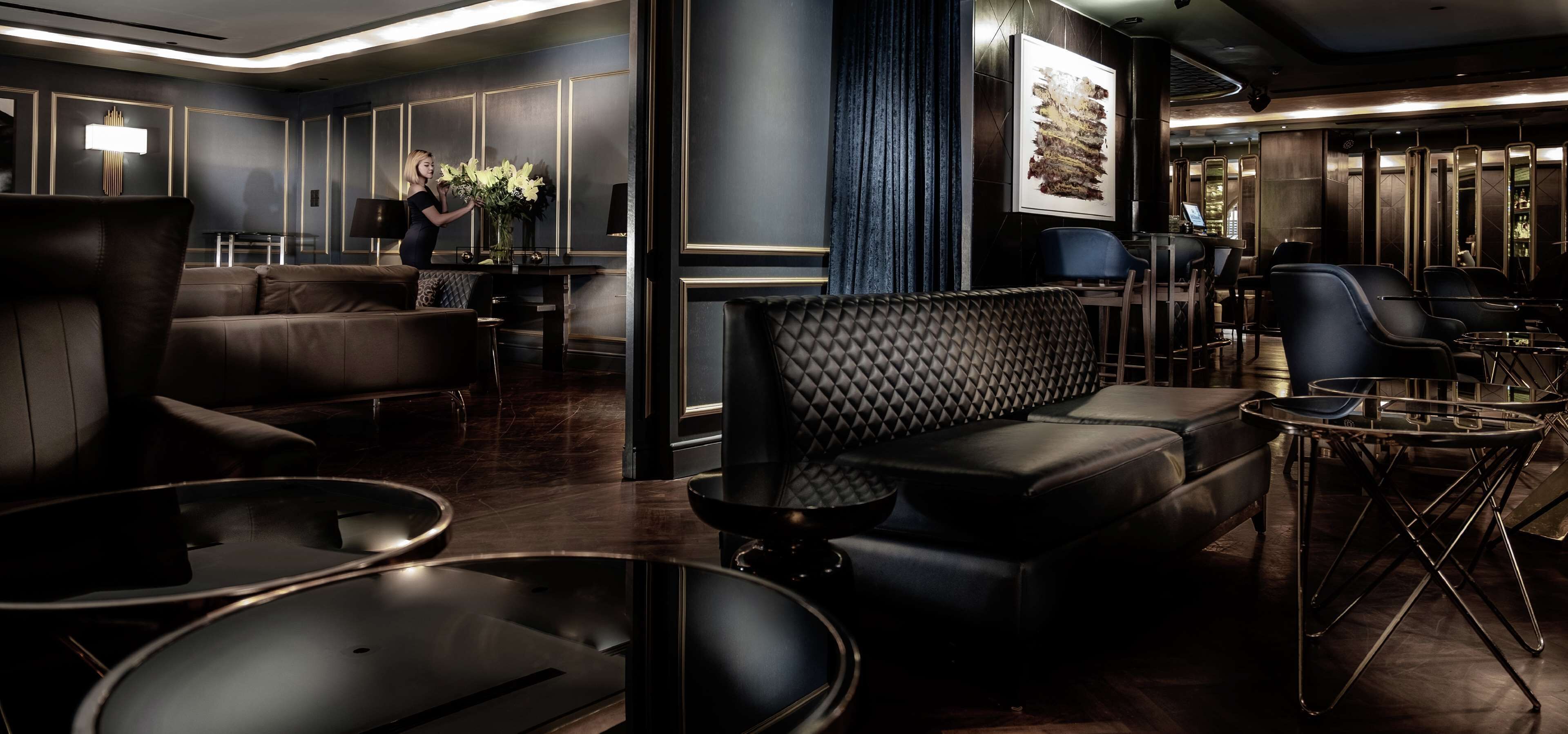 A modern lounge area with leather sofas, a coffee table, and a bar area with a piano.