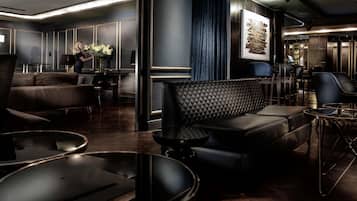 A modern lounge area with leather sofas, a coffee table, and a bar area with a piano.