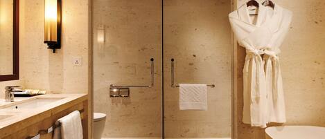 A modern bathroom with a glass-enclosed shower, a wooden vanity with a towel rack, and a white bathtub.