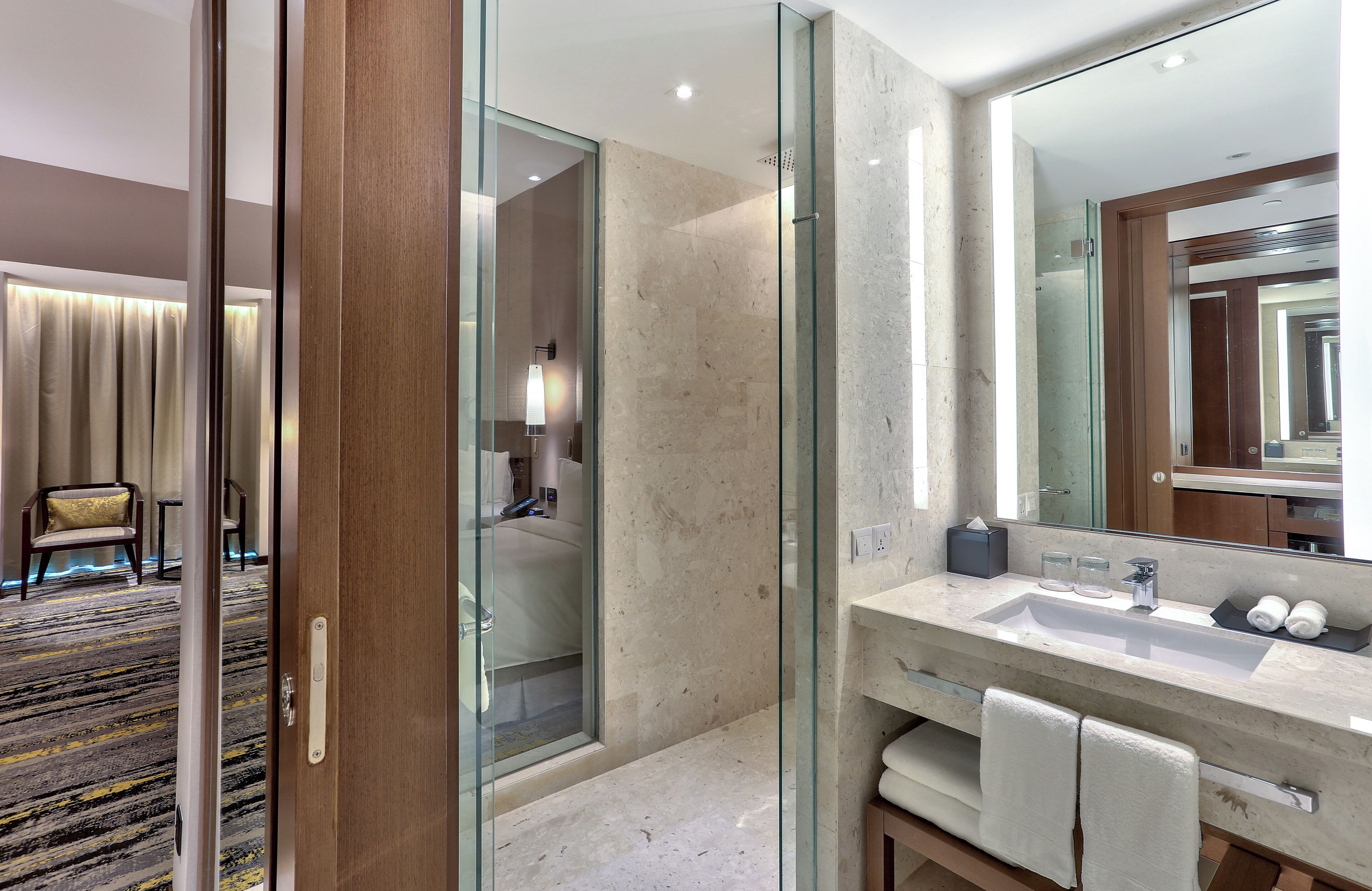 A modern bathroom with a glass shower enclosure, a marble sink, and a large mirror.