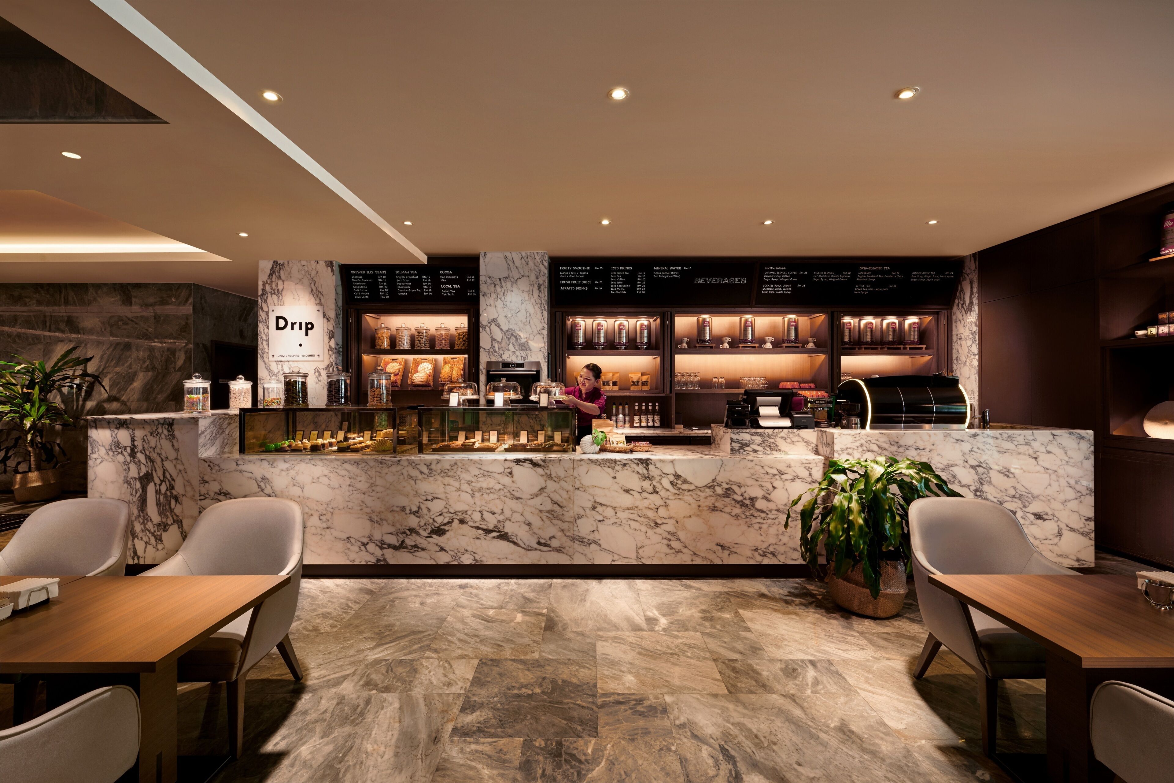 Un espace bar moderne doté de comptoirs en marbre, d’un tableau affichant le menu et d’un aménagement pour accueillir les clients.