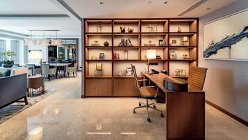 A modern office space with a wooden desk, office chair, and shelves filled with books and decorative items.