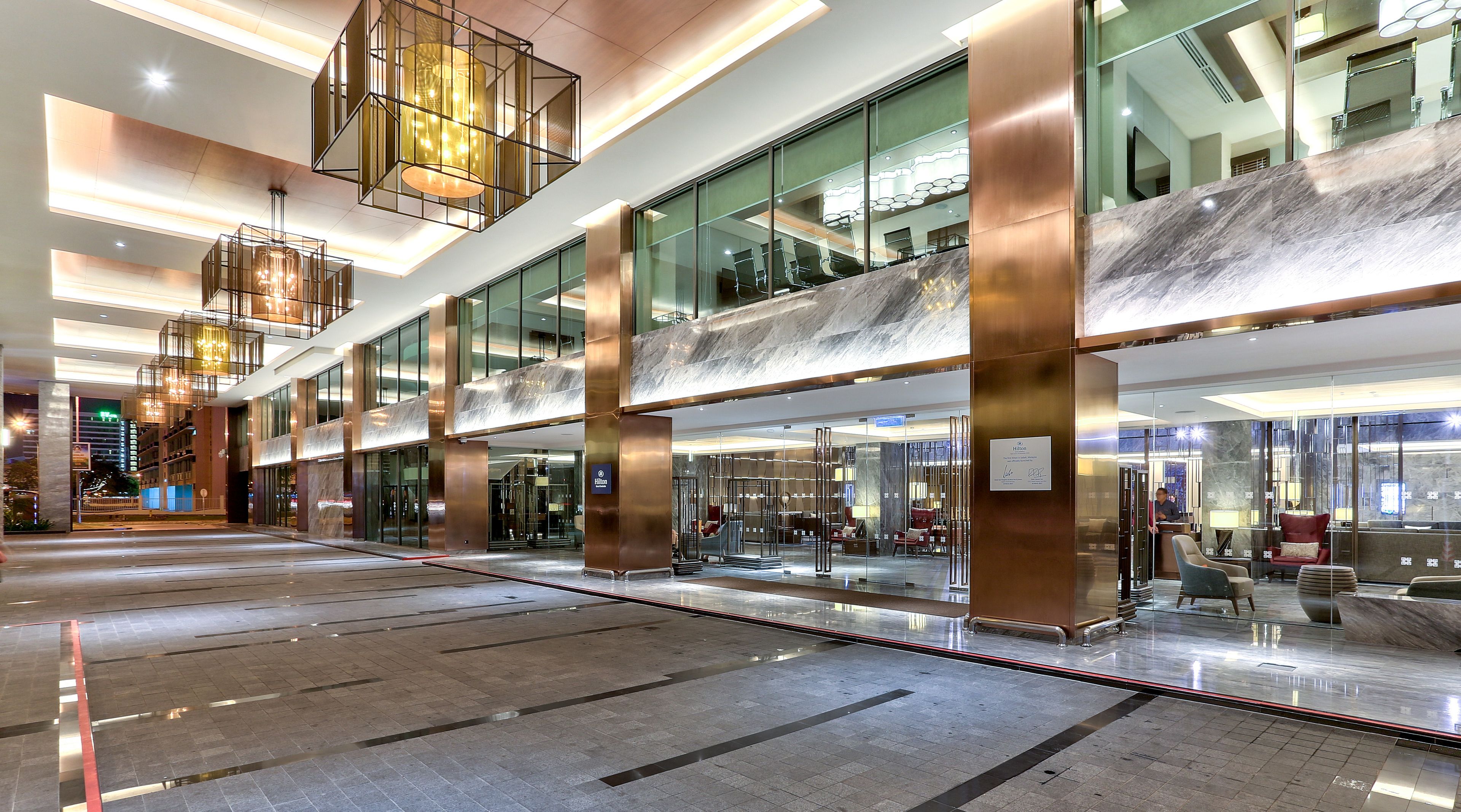 Eine moderne Hotelhalle mit großzügigem Design, großen Glasfenstern und zeitgemäßer Beleuchtung.