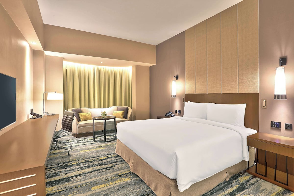 Ein Hotelzimmer mit einem großen Bett, einem Schreibtisch, einer Couch und einem kleinen Tisch.