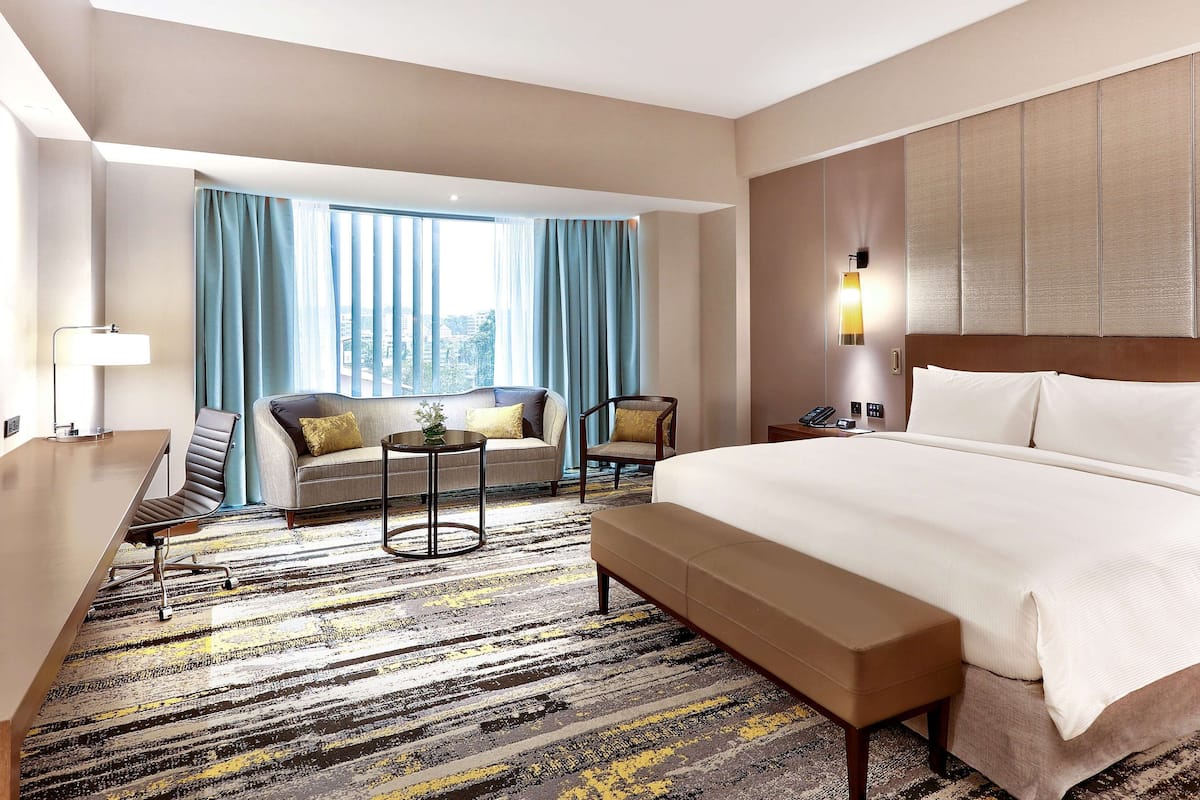 Ein Hotelzimmer mit einem großen Bett, einer Couch, einem Sessel, einem kleinen Tisch und einem Schreibtisch.