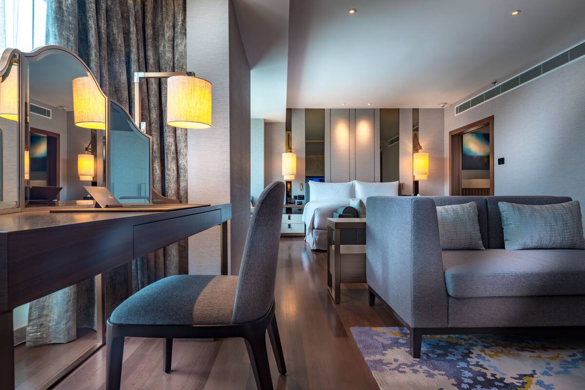 Ein modernes Hotelzimmer mit Schreibtisch, Stuhl, Sofa und einem großen Bett.