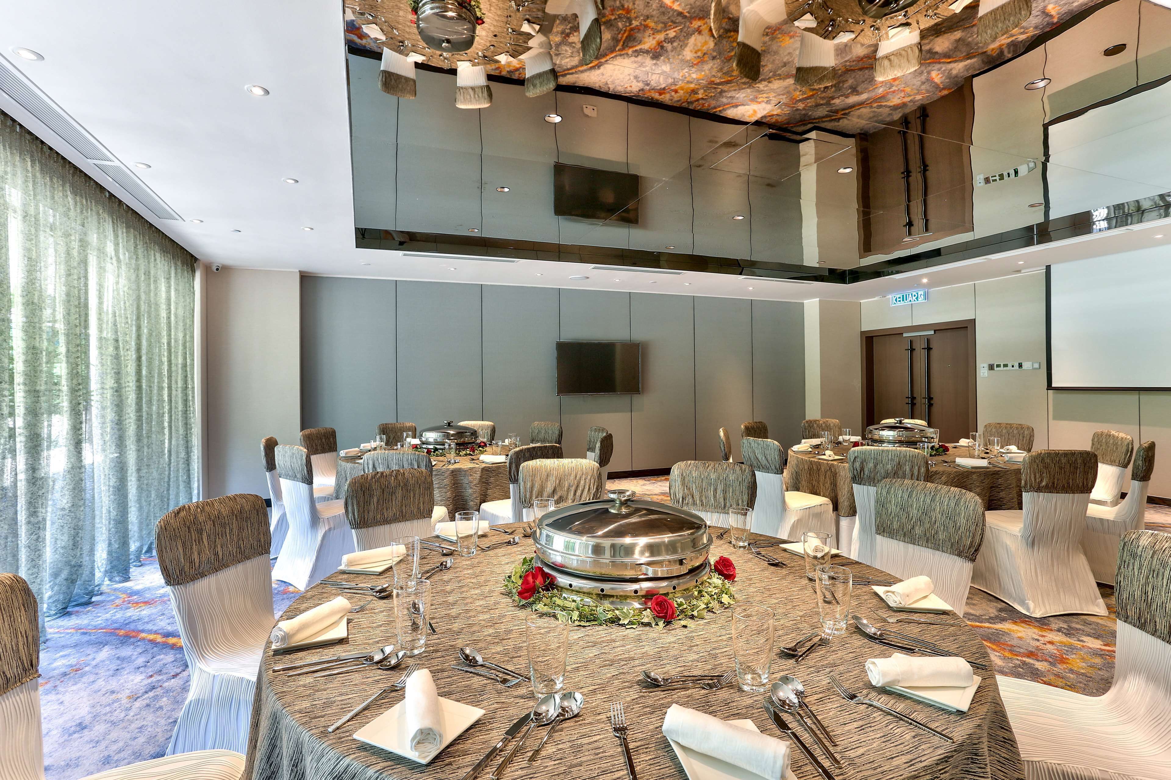 A modern conference room with round tables, white chairs, and a central table with a decorative centerpiece.