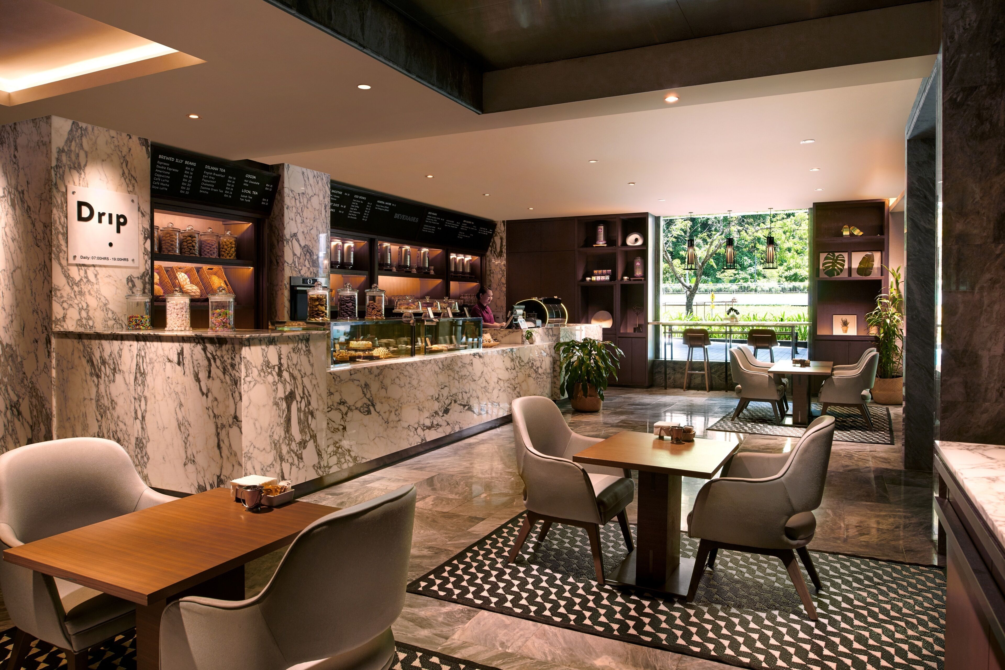 A modern cafe with marble walls, a coffee bar, and seating area with tables and chairs.