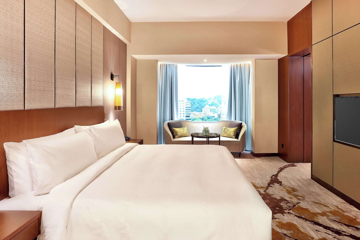 Ein Hotelzimmer mit einem großen Bett, einer Couch, einem kleinen Tisch und einem Fernseher.